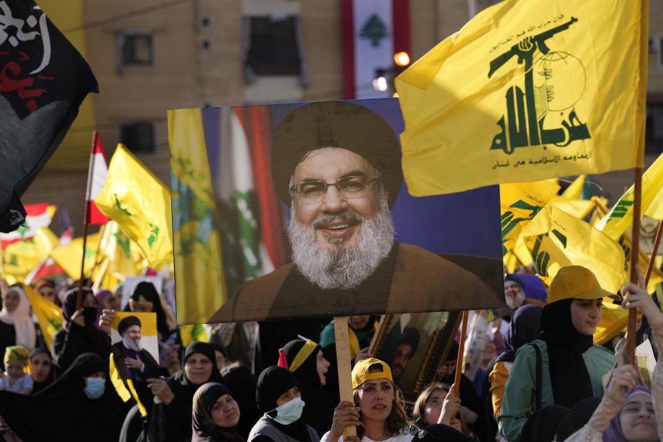 Hezbollah supporters wave portraits of Hezbollah leader Sayyed Hassan Nasrallah and their group flags, during an election campaign, in the southern suburb of Beirut, Lebanon, Tuesday, May 10, 2022. Despite a devastating economic collapse and multiple other crises gripping Lebanon, the culmination of decades of corruption and mismanagement, the deeply divisive issue of Hezbollah's weapons has been at the center of Sunday's vote for a new 128-member parliament. (AP Photo/Hussein Malla)