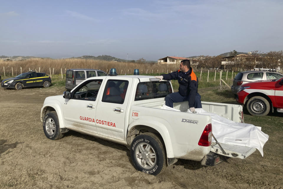 Italian Coast Guard officer sits on a vehicle with the body of a victim of a migrant boat that capsized in rough seas, in Cutro, southern Italy, Tuesday, Feb. 28, 2023. Rescue crews searched by sea and air for the dozens of people believed still missing from a shipwreck off Italy's southern coast that drove home once again the desperate and dangerous crossings of migrants seeking to reach Europe. (AP Photo/Paolo Santalucia)