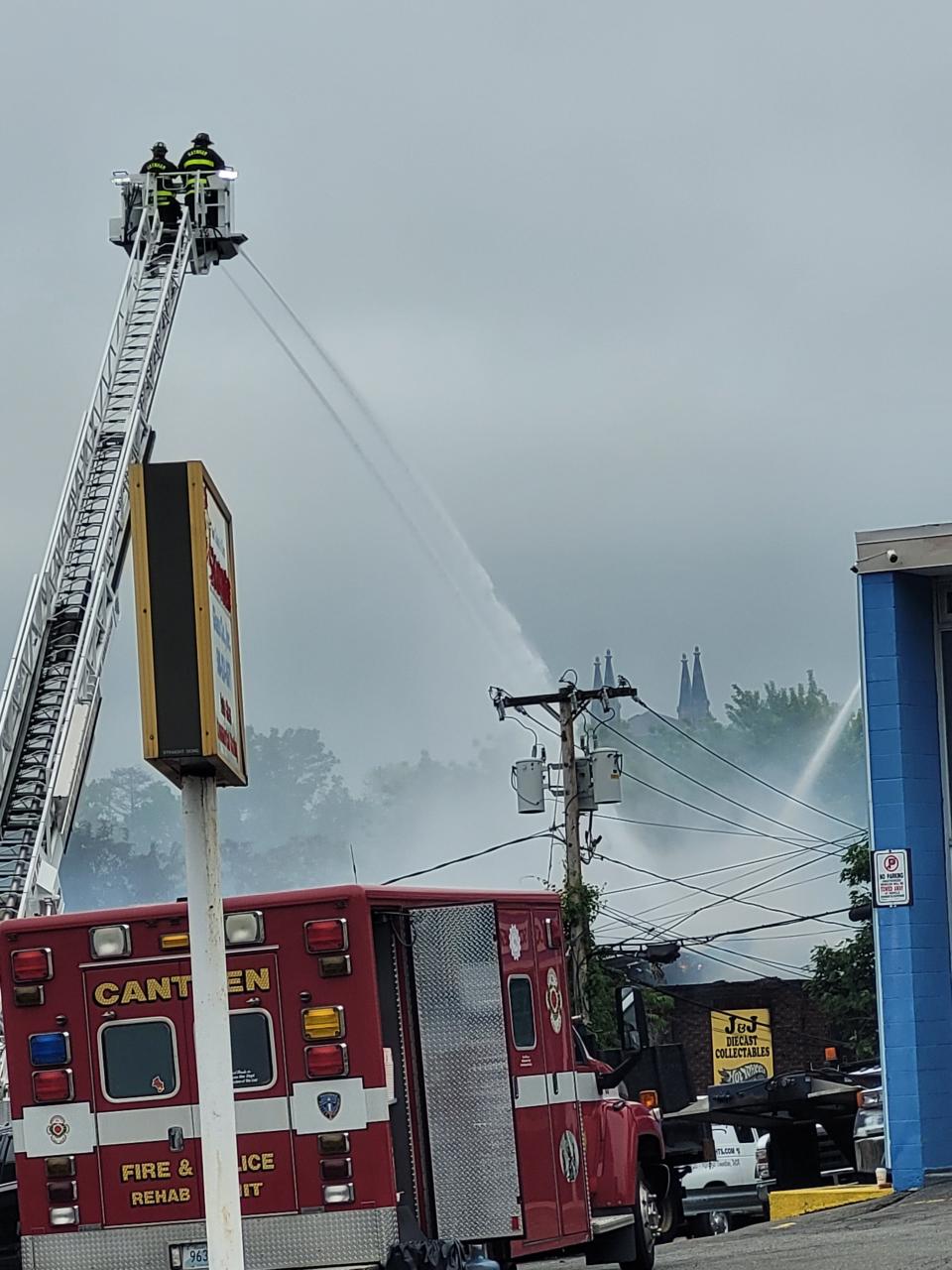 Crews work to put out a 5-alarm fire at 4 Spring Lane in Taunton on Saturday, May 28, 2022. Flames could still be seen coming through the roof of J&J Diecast Collectibles.