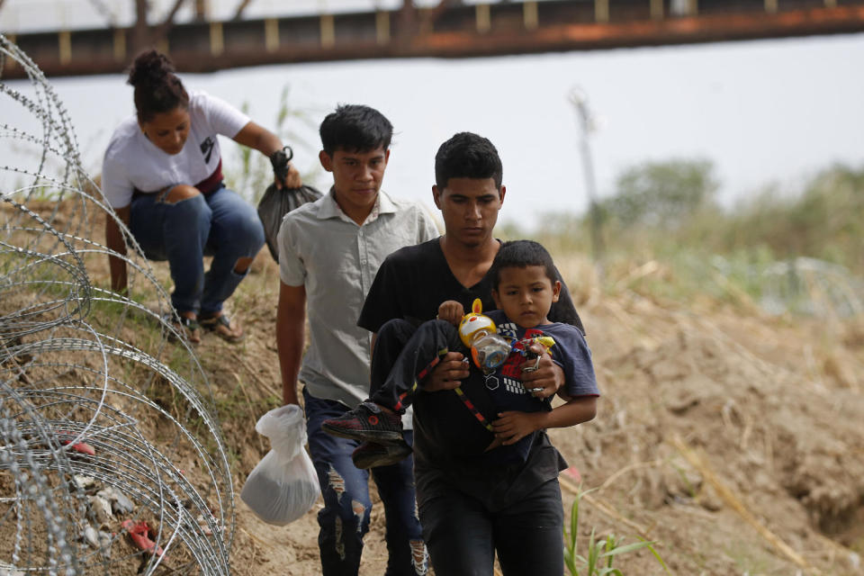 Migrants walk past barbed wire fence after crossing the Rio Grande River in Eagle Pass, Texas (Dario Lopez-Mills/AP file)