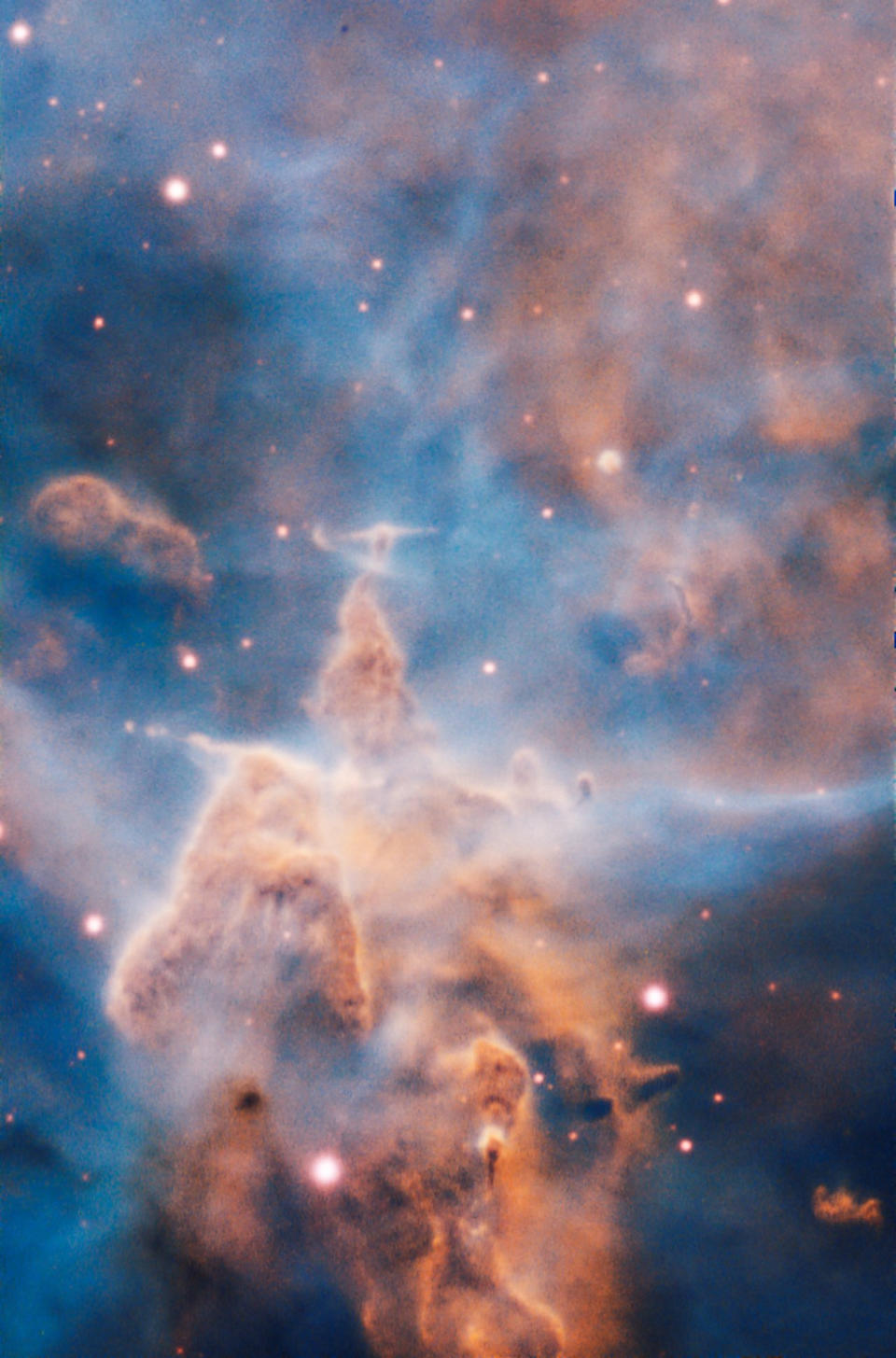 Esta cima escarpada de fantasía, envuelta por nubes tenues, parece a un paisaje extraño. Pero es un pilar de gas y polvo de tres años luz de alto que está siendo devorado por la brillante luz proveniente de estrellas brillantes cercanas. (ESO/A. McLeod)