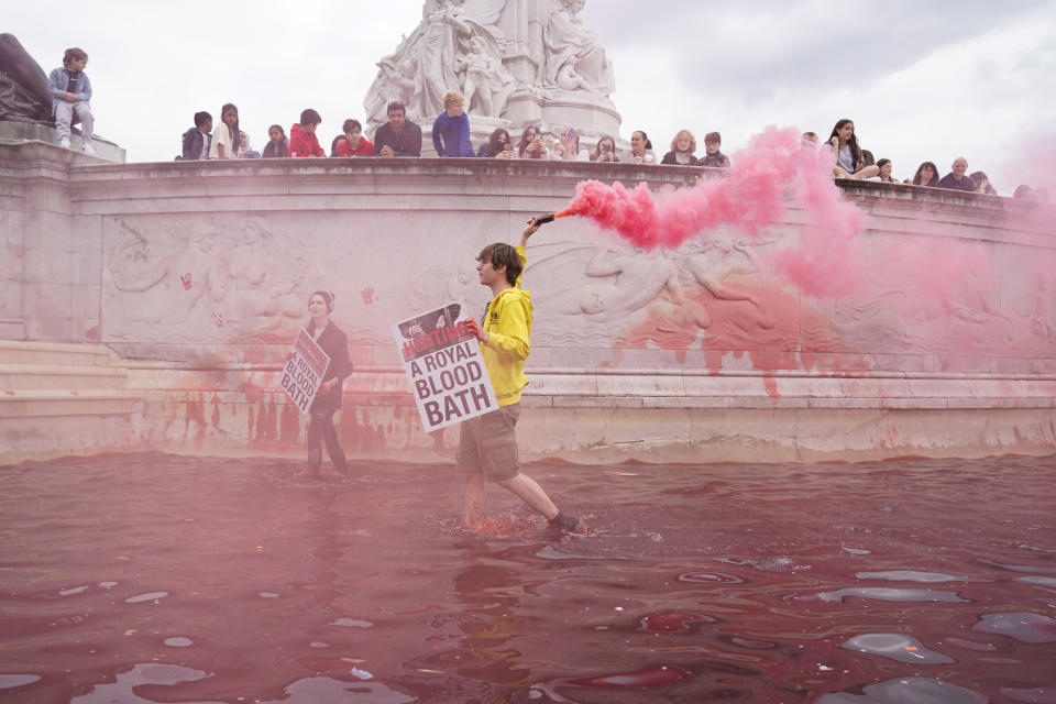 <p>Extinction Rebellion protesters let off flares as they stand in the fountain at the Queen Victoria Memorial, which they have covered in red paint, during a protest outside Buckingham Palace, London. Picture date: Thursday August 26, 2021.</p>
