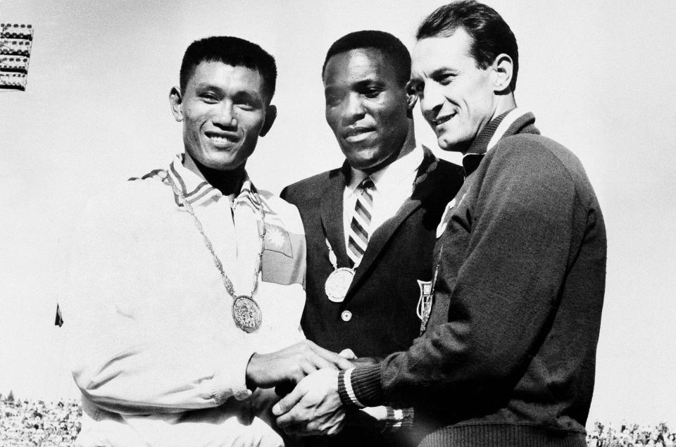 FILE - In this Sept. 7, 1960, file photo, Rafer Johnson of Kingsburg, Calif., is flanked by runners-up, Chuan-Kwang Yang, left, of Taiwan, and Vasily Kuznetsov of Russia, as they join in three-way handshake after receiving medals for the decathlon event of the Olympics in Rome, Italy. Rafer Johnson, who won the decathlon at the 1960 Rome Olympics and helped subdue Robert F. Kennedy's assassin in 1968, died Wednesday, Dec. 2, 2020. He was 86. He died at his home in the Sherman Oaks section of Los Angeles, according to family friend Michael Roth. (AP Photo)