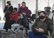 A mother stands with her son as they wait for him to get a shot of the Moderna vaccine for COVID-19, donated by the US government, at a health center in Quilmes Argentina, Tuesday, Aug. 3, 2021. Argentina is vaccinating youths with pre-existing conditions, between ages 12 and 17. ​(AP Photo/Gustavo Garello)