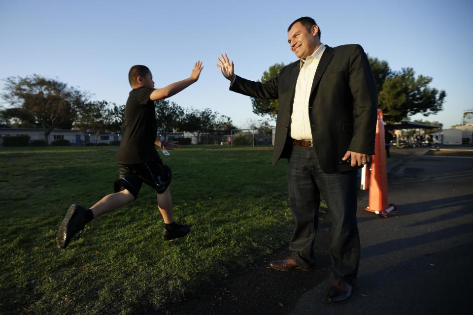 In this March 14, 2014 picture, Rice Elementary School Principal Ernesto Villanueva slaps hands with students during an early morning running program at an elementary school in Chula Vista, Calif. Amid alarming national statistics showing an epidemic in childhood obesity, hundreds of thousands of students across the country are being weighed and measured. Beltran son’s Chula Vista Elementary School District is being touted as a model for its methods that have resulted in motivating the community to take action. (AP Photo/Gregory Bull)