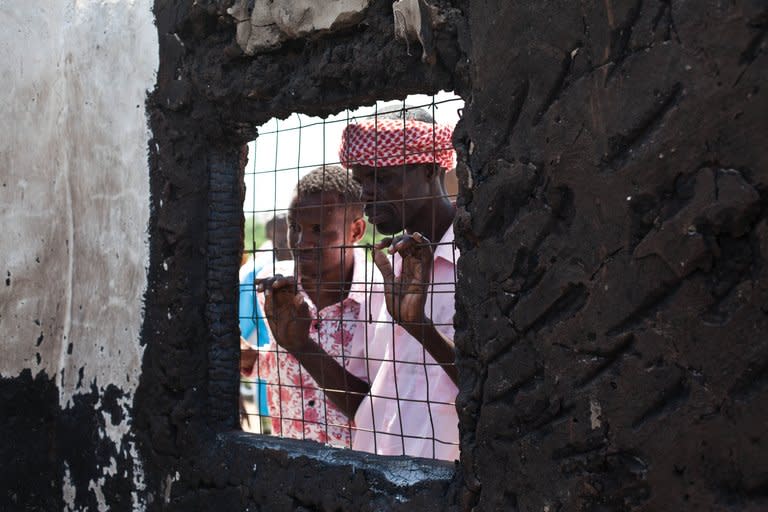 Two Orma men look into a burnt house on December 22, 2012 in Kipao, in the Tana delta region of southeast Kenya. At least 10 people were killed and several wounded in a retaliatory dawn raid Thursday in the Tana River delta region, the latest violence to flare up in an area where scores died in clashes last year, Kenya Red Cross said