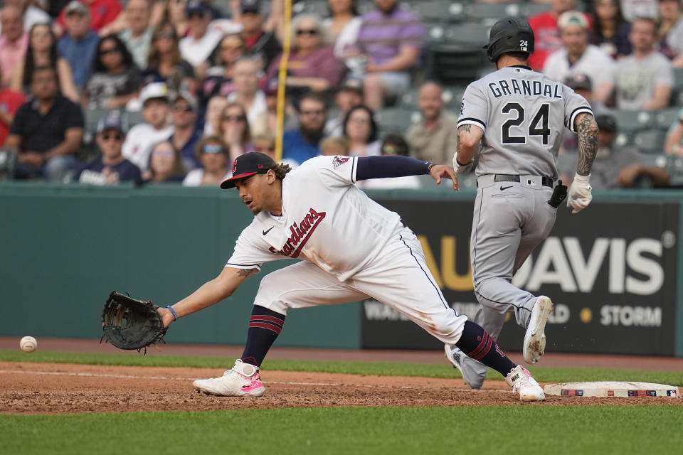 Cleveland Guardians first baseman Josh Naylor, left, reaches for the ball as Chicago White Sox's Yasmani Grandal (24) is safe at first base on a fielding error by third baseman Jose Ramirez in the seventh inning of a baseball game Tuesday, May 23, 2023, in Cleveland. (AP Photo/Sue Ogrocki)