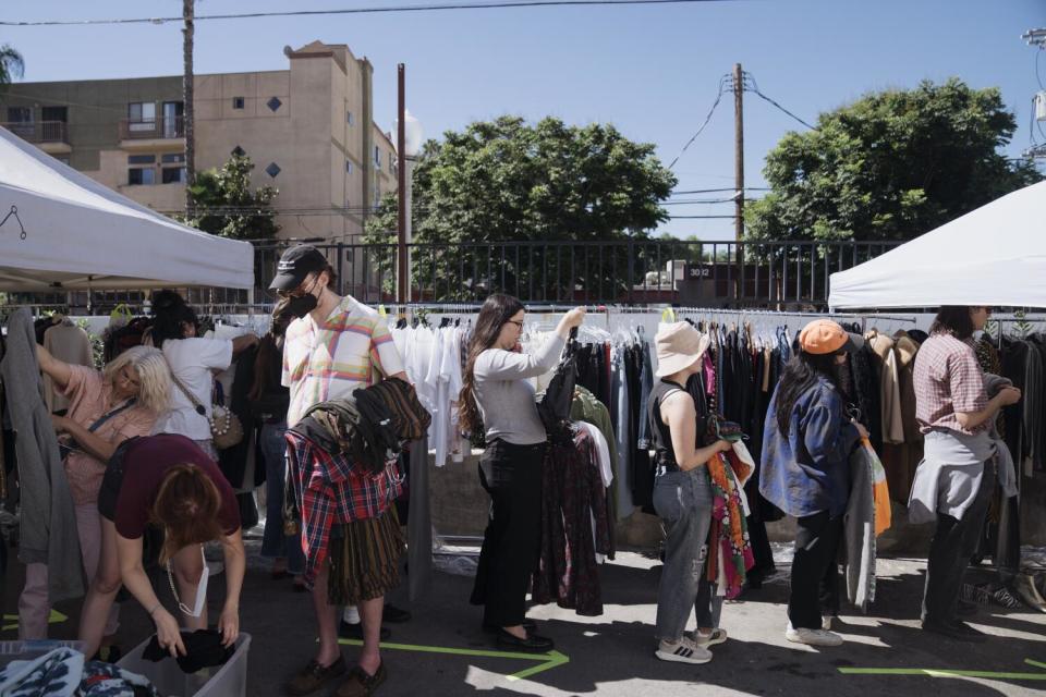 People stand in line outdoors holding items of clothing.