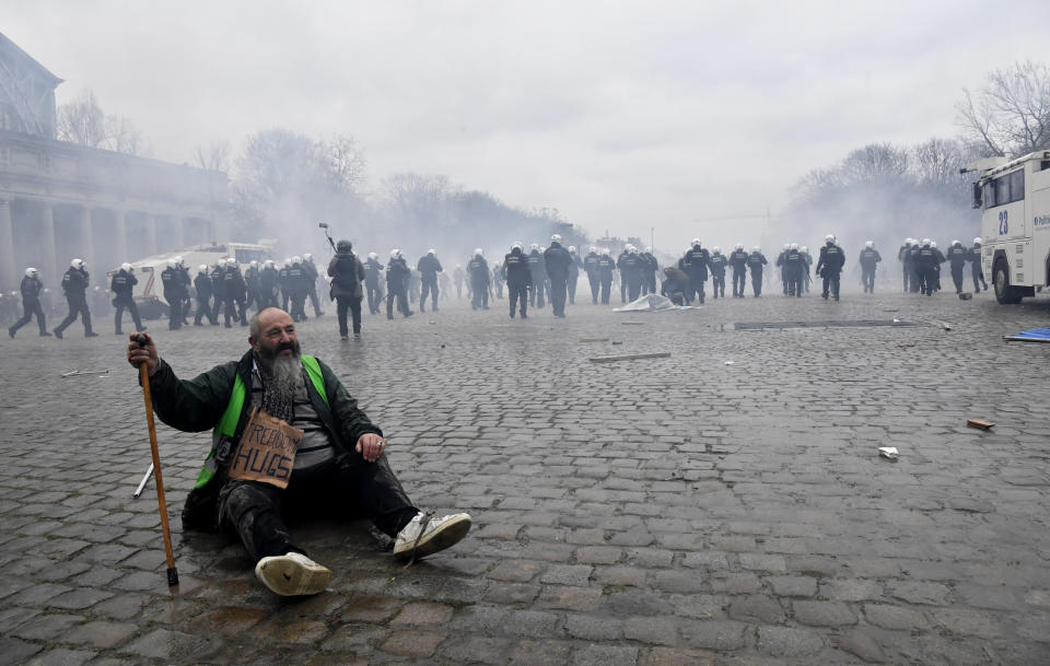 A man sits on the pavement as police confront protestors during a demonstration against COVID-19 measures in Brussels, Sunday, Jan. 23, 2022. Demonstrators gathered in the Belgian capital to protest what they regard as overly extreme measures by the government to fight the COVID-19 pandemic, including a vaccine pass regulating access to certain places and activities and possible compulsory vaccines. (AP Photo/Geert Vanden Wijngaert)