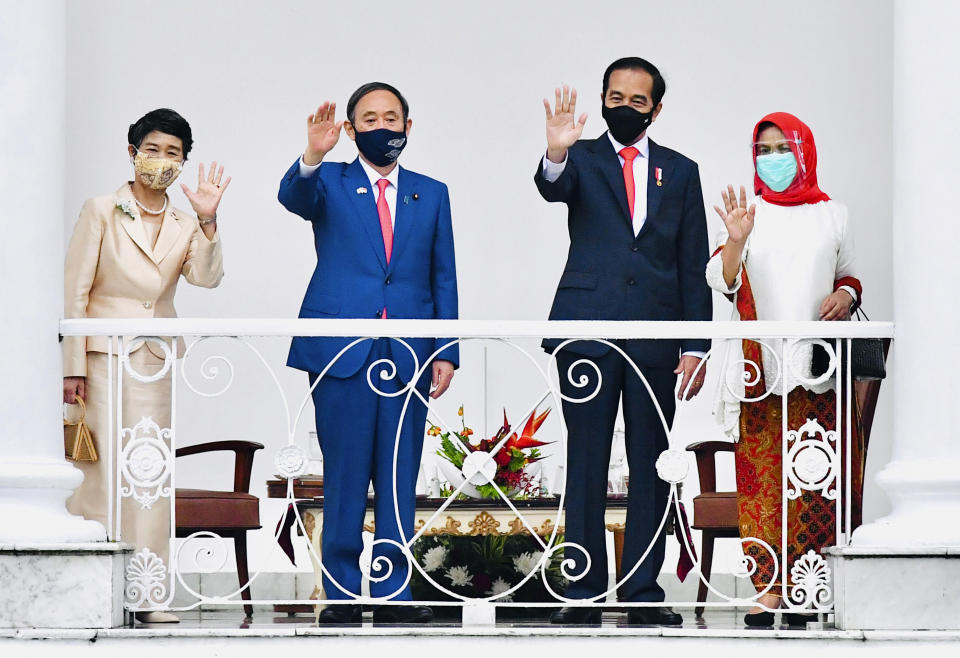 In this photo released by Indonesian Presidential Palace, Japanese Prime Minister Yoshihide Suga, second left, Indonesian President Joko Widodo, second right, Suga's wife Mariko, left, and Widodo's wife Iriana wave during their meeting at the Presidential Palace in Bogor West Java, Indonesia, Tuesday, Oct 20, 2020. (Laily Rachev/Indonesian Presidential Palace via AP)