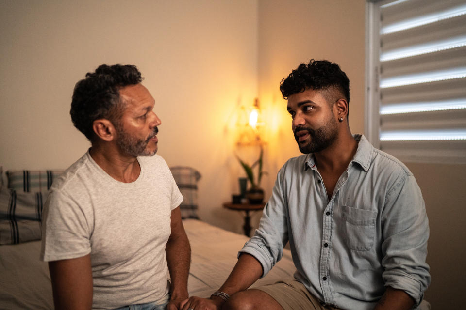 Gay couple talking on the bed at home (Getty)