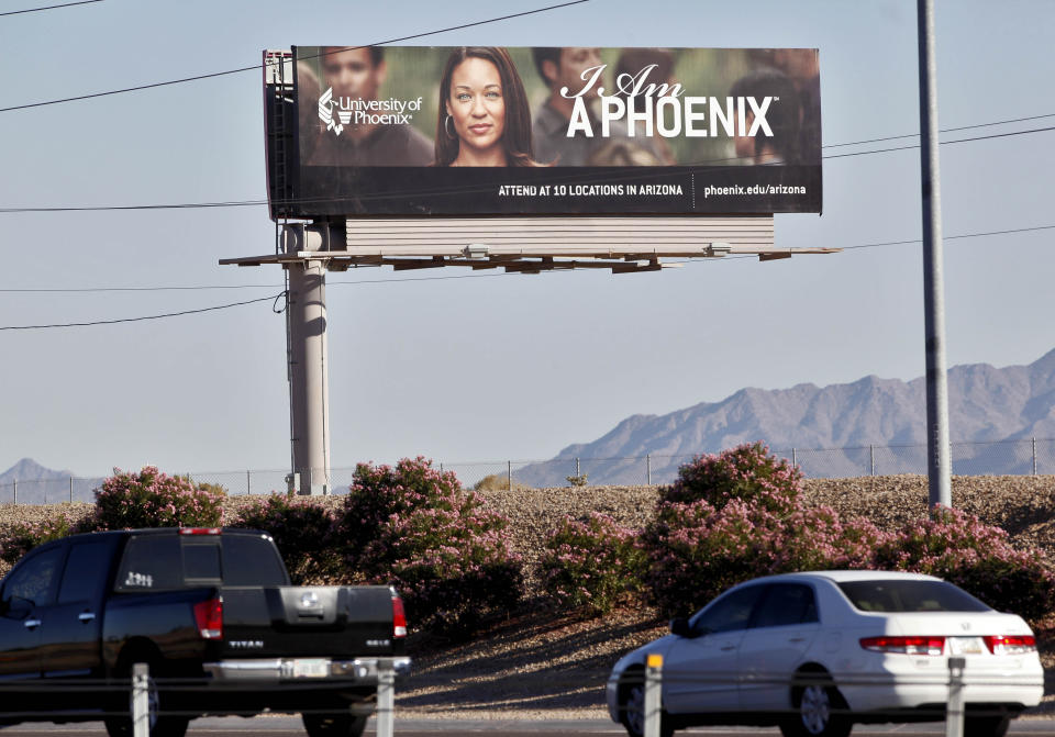FILE - In this Nov 24, 2009 file photo, a University of Phoenix billboard is shown in Chandler, Ariz. Some of the nation’s largest for-profit colleges are ramping up advertising, hiring recruiters and offering discounts for online classes as they predict that the coronavirus will steer more Americans back to school, helping revive the industry. (AP Photo/Matt York, File)
