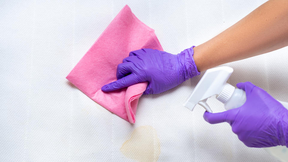 Woman cleaning a mattress stained by sweat