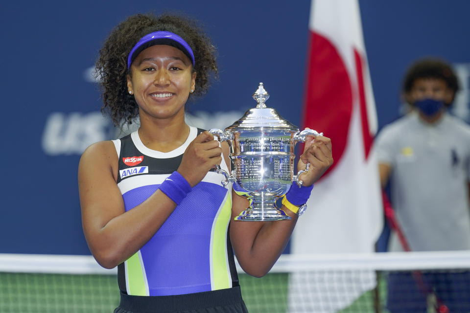 FILE - In this Sept. 12, 2020, file photo, Naomi Osaka, of Japan, holds up the championship trophy after defeating Victoria Azarenka, of Belarus, in the women's singles final of the US Open tennis championships, in New York. Osaka's victory in the U.S. Open helped raised the issue of racial injustice in the United States. Before each of her matches, she wore a mask with the names of seven Black Americans who died as victims of violence. The daughter of a Japanese mother and Haitian father, she has become a leader of the Black Lives Matter movement. (AP Photo/Seth Wenig)