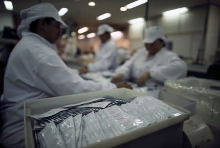Condoms are seen as employees work in a factory in Buenos Aires