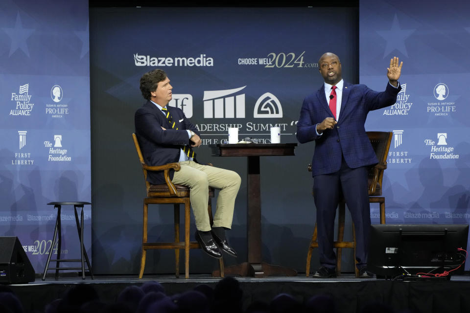 Republican presidential candidate Sen. Tim Scott, R-S.C., speaks during the Family Leadership Summit as moderator Tucker Carlson, left, looks on, Friday, July 14, 2023, in Des Moines, Iowa. (AP Photo/Charlie Neibergall)