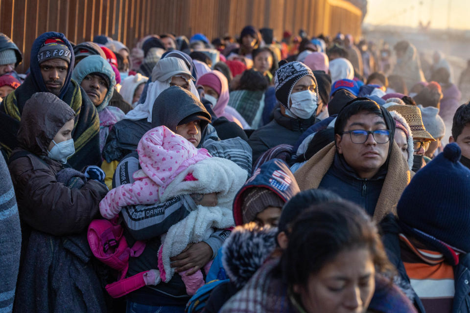 Immigrants bundle up against the cold after spending the night camped alongside the U.S.-Mexico border fence on December 22, 2022 in El Paso, Texas.