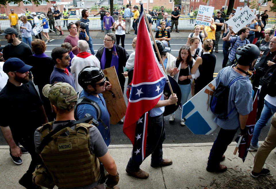 A white nationalist carries the Confederate flag as he walks past counter-demonstrators in Charlottesville, Virginia, on Aug. 12 (Photo: Joshua Roberts / Reuters)