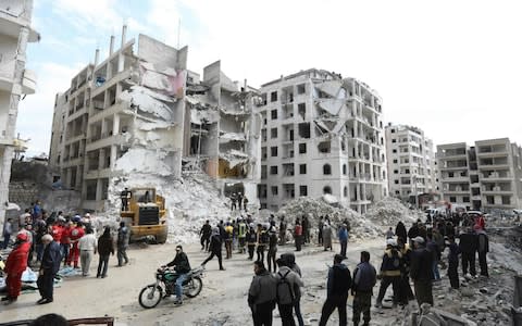 Syrian onlookers gather around rescue teams clearing the rubble in the morning of April 10, 2018 in the northwestern city of Idlib. - Credit: AFP