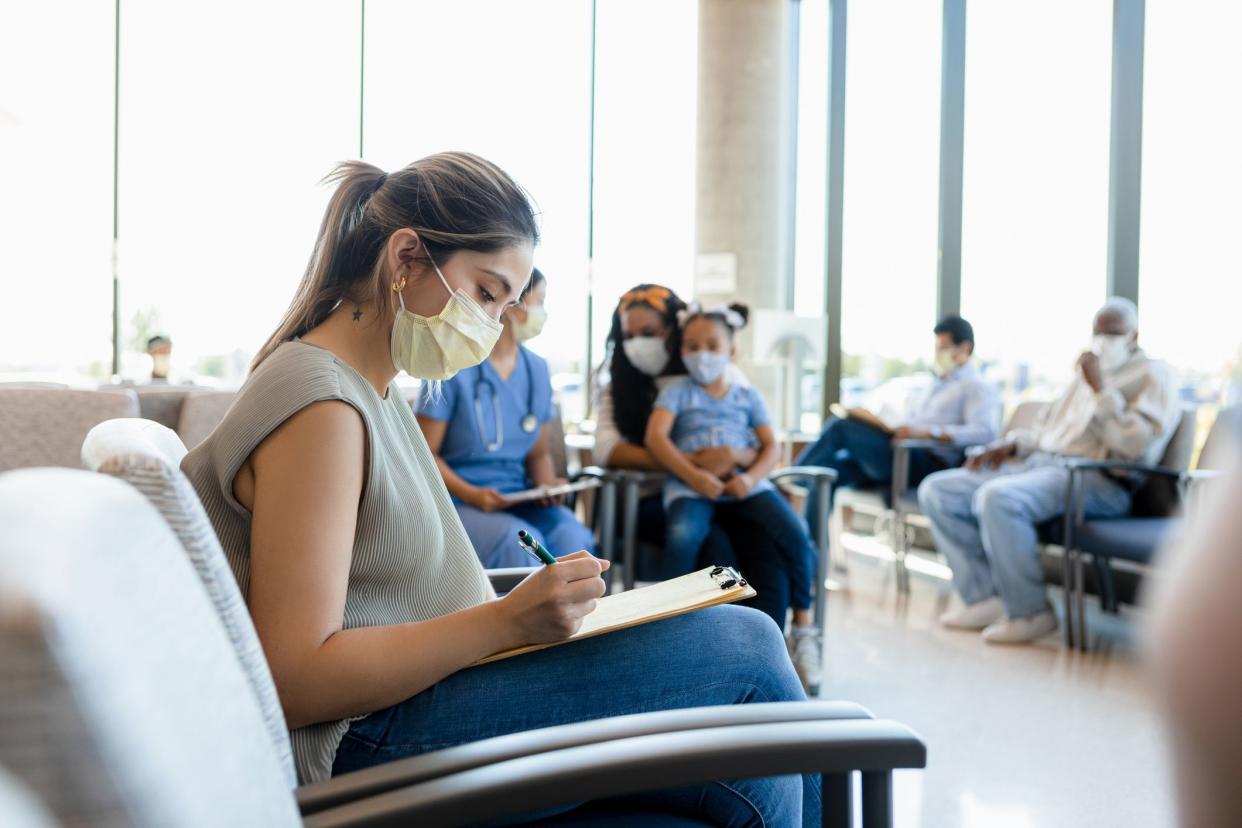 Everyone wears the required protective masks as they wait in the busy hospital waiting room.