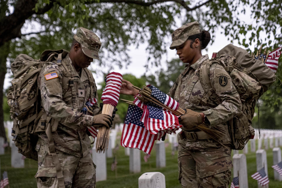 Members of the 3rd U.S. Infantry Regiment also known as The Old Guard, place flags in front of each headstone for "Flags-In" at sunrise at Arlington National Cemetery in Arlington, Thursday, May 25, 2023, to honor the Nation's fallen military heroes ahead of Memorial Day. (AP Photo/Andrew Harnik)