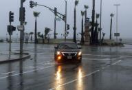 A car turns off Pacific Coast Highway during a downpour in the Pacific Palisades area of Los Angeles, Friday morning, Jan. 20, 2017. The second in a trio of storms has brought rain, heavy at times, over a wide area of California. The National Weather Service has issued a flood advisory for San Luis Obispo County as moderate to heavy rain falls on the Central Coast.(AP Photo/Reed Saxon)