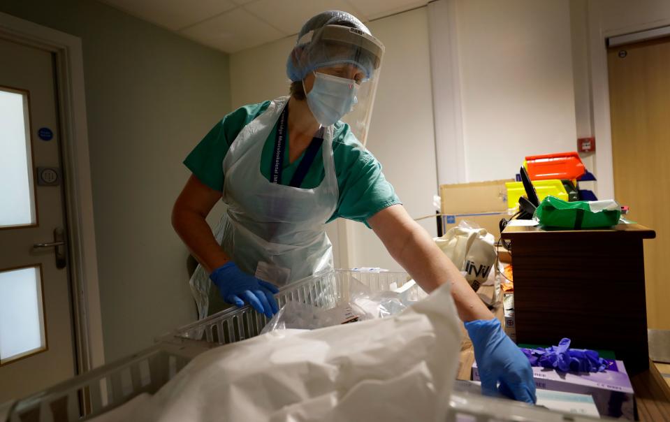 Consultant Rheumatologist Frances Hall gets dressed in PPE before entering a ward where coronavirus patients are taking part in the TACTIC-R trial, at Addenbrooke's hospital in Cambridge, England on May 21, 2020, during the novel coronavirus COVID-19 pandemic. - The new trial known as TACTIC-R is testing whether existing drugs will help prevent the body's immune system from overreacting, which scientists hope could prevent organ failure and death in COVID-19 patients. (Photo by Kirsty Wigglesworth / POOL / AFP) (Photo by KIRSTY WIGGLESWORTH/POOL/AFP via Getty Images)