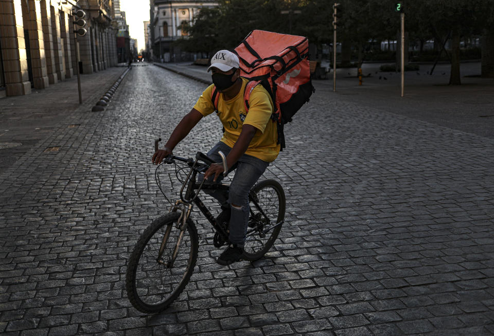 Un ciclista de reparto de comida recorre una calle desierta durante un bloqueo reinstalado para ayudar a contener la propagación del COVID-19, en Santiago de Chile, el sábado 27 de marzo de 2021. (AP Foto/Esteban Félix).