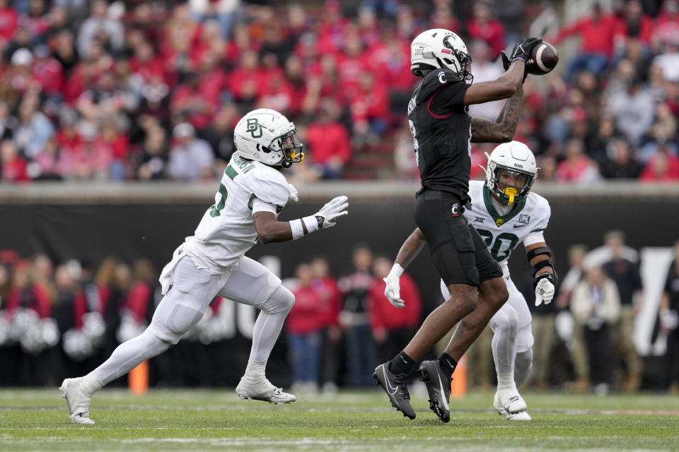 Cincinnati wide receiver Xzavier Henderson, center, makes a catch against Baylor safety Devin Lemear (20) during the second half of an NCAA college football game, Saturday, Oct. 21, 2023, in Cincinnati. (AP Photo/Jeff Dean)