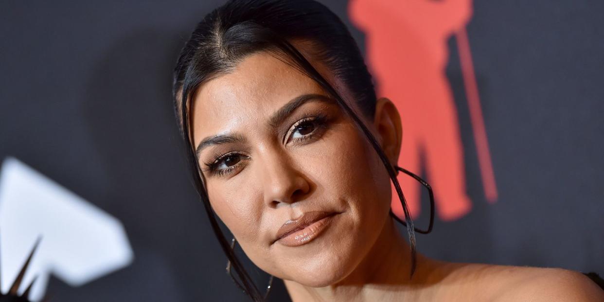 close up of kourtney kardashian with hair up and hoop earrings on a red carpet