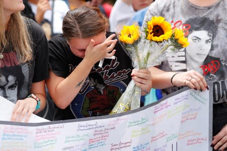 A fan wipes away tears after a moment of silence as people gather at Forest Lawn Cemetery ten years after the death of child star turned King of Pop, Michael Jackson, in Glendale, California,