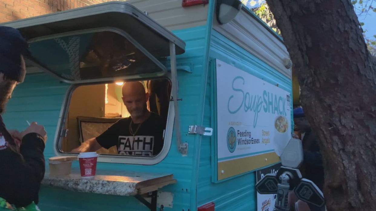 Bobby Reaume serves soup and a coffee to someone at Windsor's Soup Shack trailer. (Kathleen Saylors/CBC - image credit)