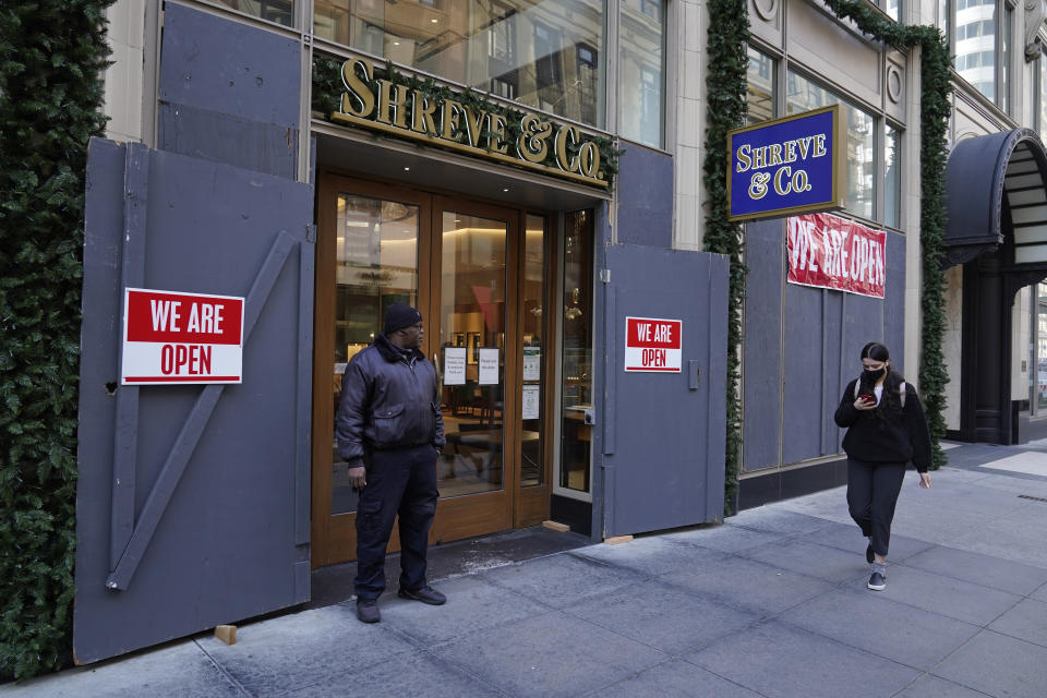 A security guard stands outside the heavily boarded Shreve & Co. jewelry store in San Francisco, Thursday, Dec. 2, 2021. In San Francisco, homeless tents, open drug use, home break-ins and dirty streets have proliferated during the pandemic. The quality of life crimes and a laissez-faire approach by officials to brazen drug dealing have given residents a sense the city is in decline. (AP Photo/Eric Risberg)