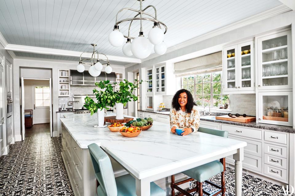 Shonda Rhimes, wearing a Chanel sweater, in the kitchen of her Los Angeles home. Ralph Lauren for Visual comfort chandeliers; calacatta marble island; on floors, custom tile by Native Tile & Ceramics. Fashion styling by Dana Asher Levine.