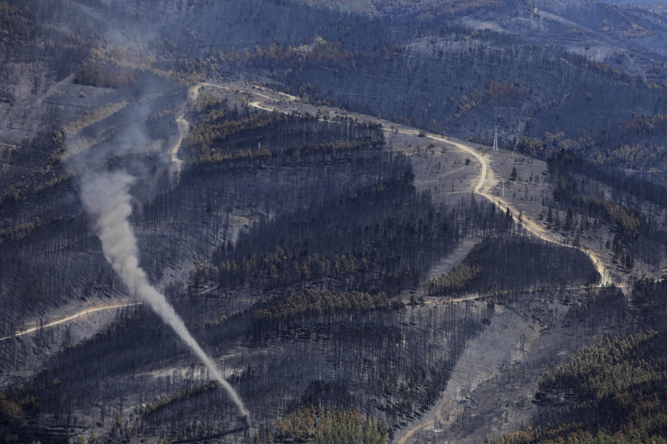 A cloud of smoke rises during a wildfire in the Serra da Estrela national park, Portugal on Thursday, Aug. 18, 2022. Authorities in Portugal said Thursday they had brought under control a wildfire that for almost two weeks raced through pine forests in the Serra da Estrela national park, but officials warned a dangerous new heat wave is about to arrive. (AP Photo/Joao Henriques)