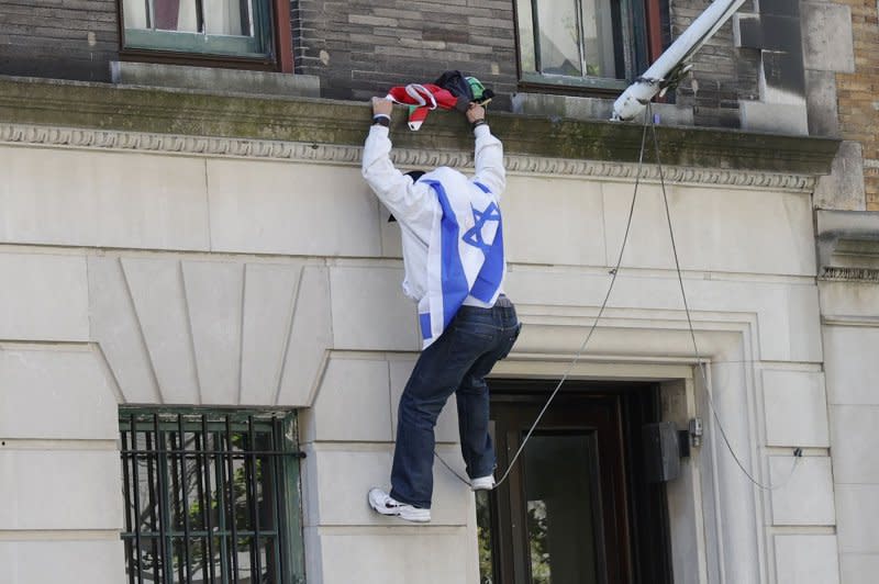 A Pro-Israeli protester takes down a Palestinian flag outside of Columbia University in New York on Friday. The University announced that classes would be held remotely starting Monday. Photo by John Angelillo/UPI