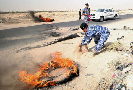 Iraqi policemen threw sand to put out tyres that the protesters had set ablaze during a protest at the main entrance to the giant Zubair oilfield near Basra, Iraq July 17, 2018. REUTERS/Essam al-Sudani