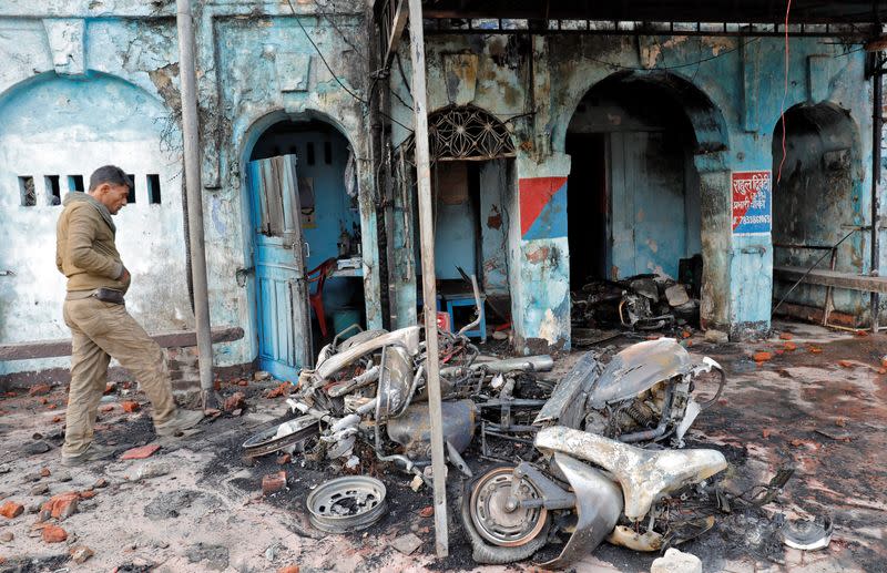 Man walks past charred motorbikes after a police post was set on fire by demonstrators during a protest against a new citizenship law, in Lucknow