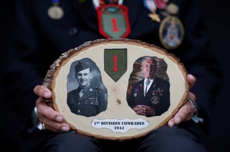 Charles Norman Shay, 94, a Penobscot Native American Indian WWII veteran, poses holding pictures of himself and his first division comrade Edward Morozewicz as he attends an interview with Reuters in Bretteville l'Orgueilleuse