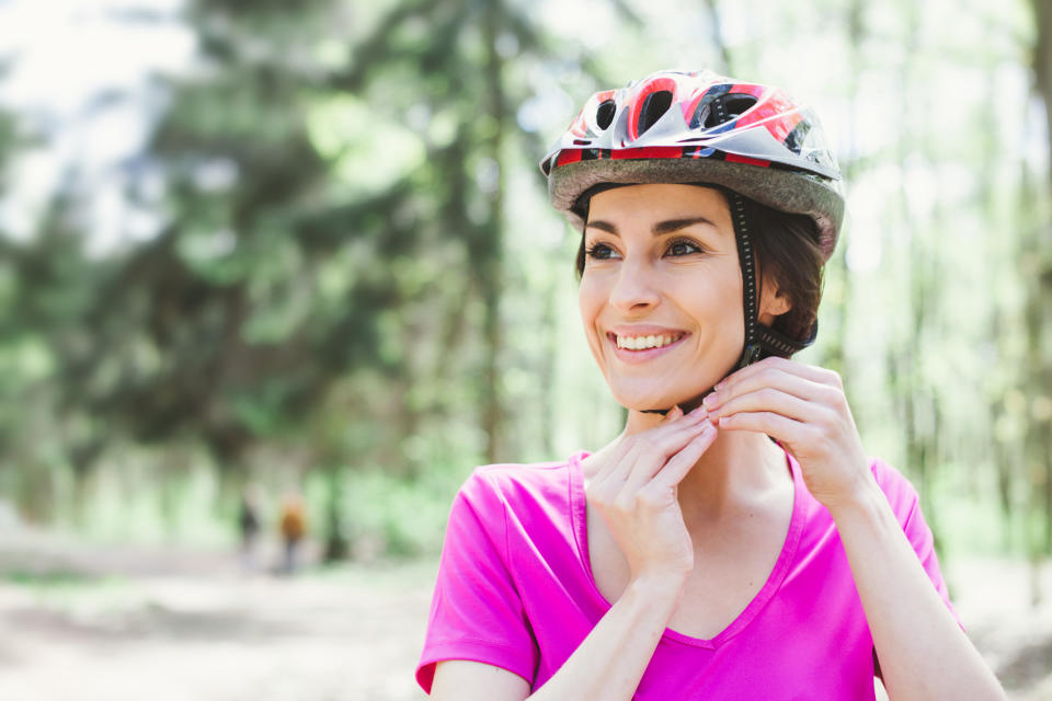 Woman Putting Biking Helmet on Outside During Bicycle Ride.