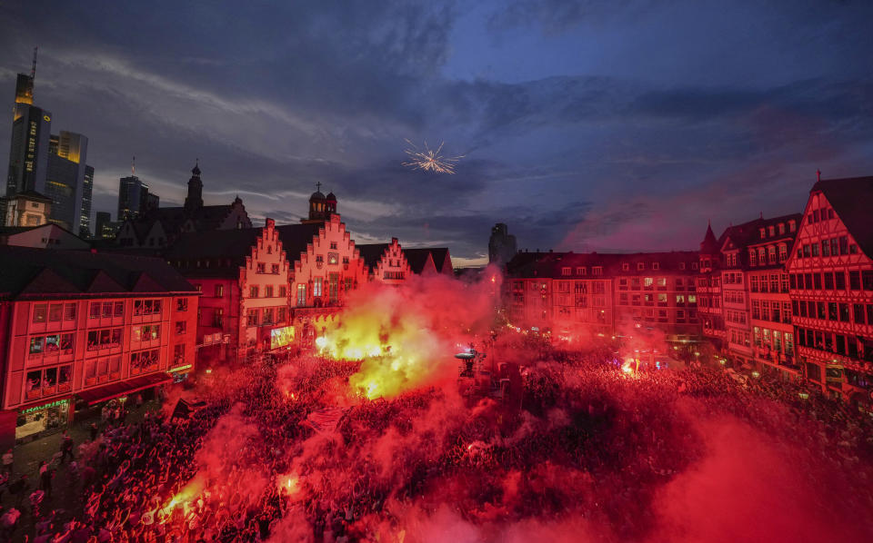 The supporters of the German Bundesliga soccer team of Eintracht Frankfurt light fireworks as they celebrate the arrival of the team for a welcome event in Frankfurt, Germany, Thursday, May 19, 2022, the day after Eintracht Frankfurt won the Europa League final match against Scottish team Glasgow Rangers FC in Seville.(AP Photo/Michael Probst)