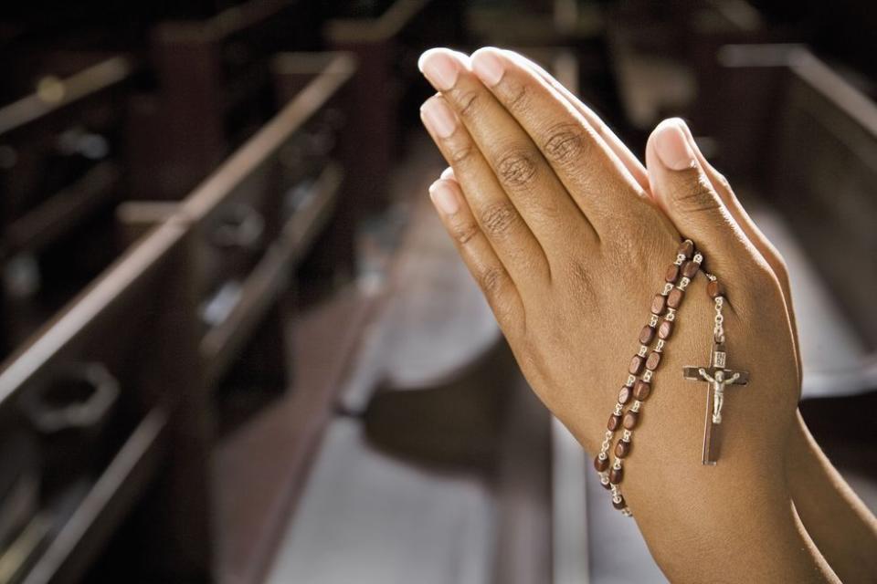 hands praying for healing in church with rosary