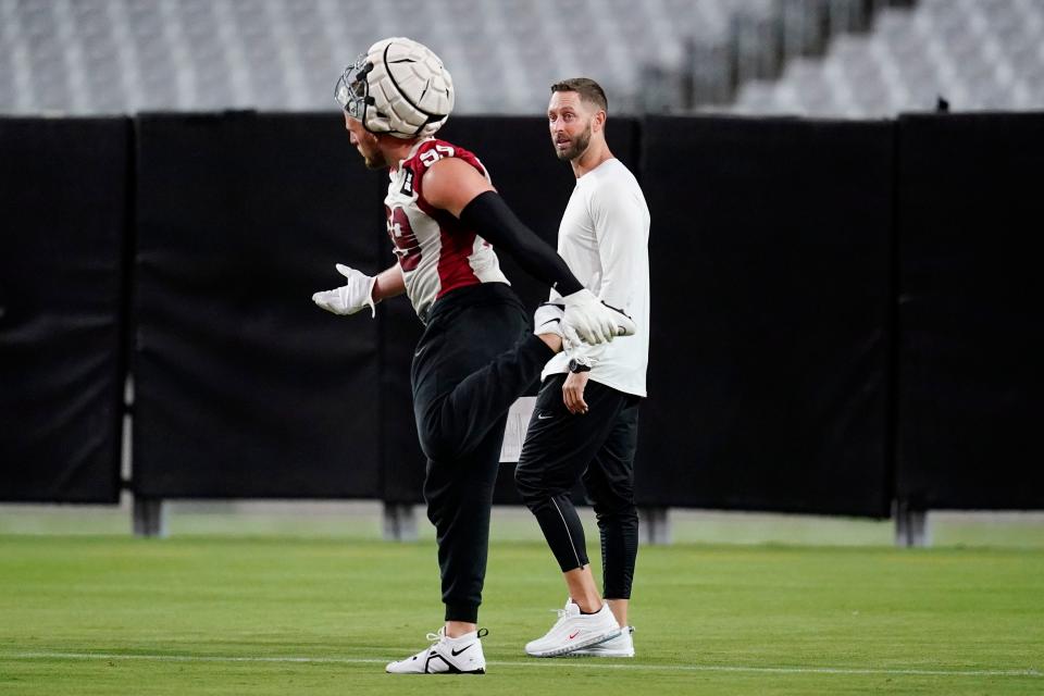 Arizona Cardinals NFL football head coach Kliff Kingsbury, right, talks with Cardinals defensive end J.J. Watt (99) as Watt stretches out during practice Thursday, July 28, 2022, in Glendale, Ariz. (AP Photo/Ross D. Franklin)