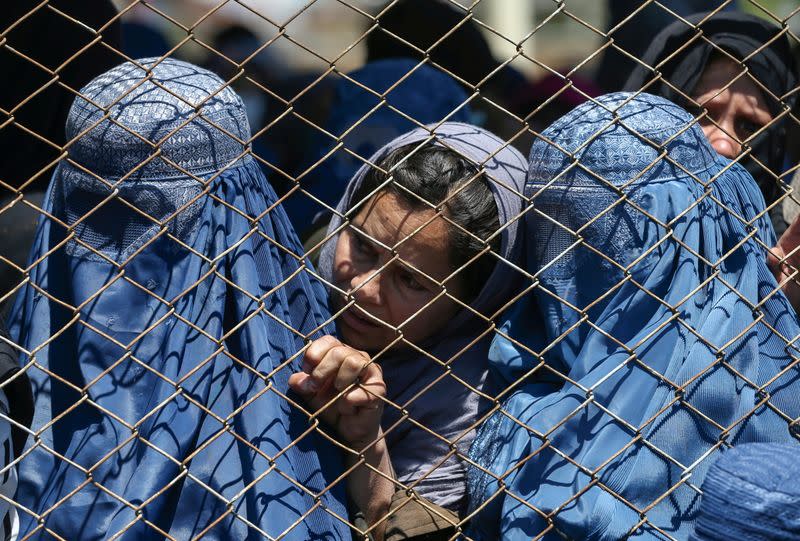 FILE PHOTO: Afghan women wait to receive free wheat donated by the Afghan government during a quarantine, amid concerns about the coronavirus disease (COVID-19) in Kabul