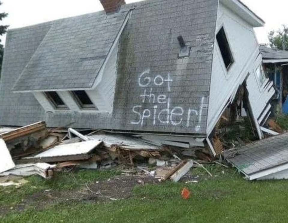 A collapsed house with "Got the spider!" spray-painted on the side