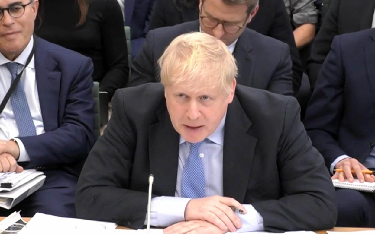 A video grab from footage broadcast by the UK Parliament's Parliamentary Recording Unit (PRU) shows former British Prime Minister Boris Johnson looking at photographs of him in Downing Street on November 13, 2021, as he attends a Parliamentary Privileges Committee hearing, in central London on March 22, 2023. - -/STF/AFP