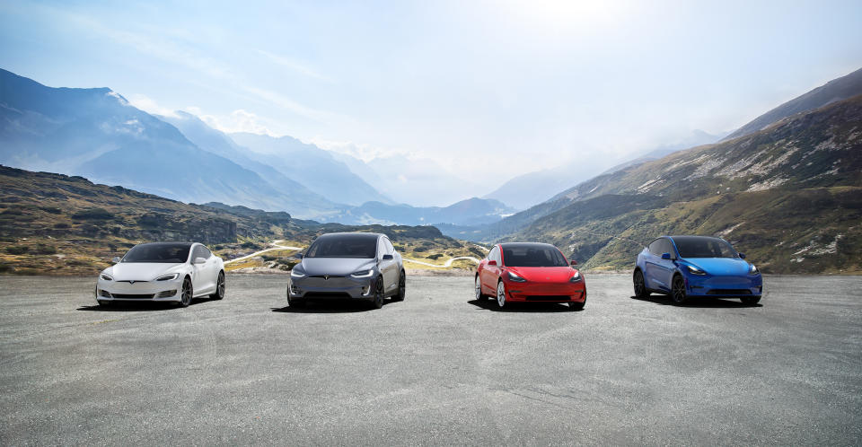 Four models of Tesla cars lined up, with mountains in the background