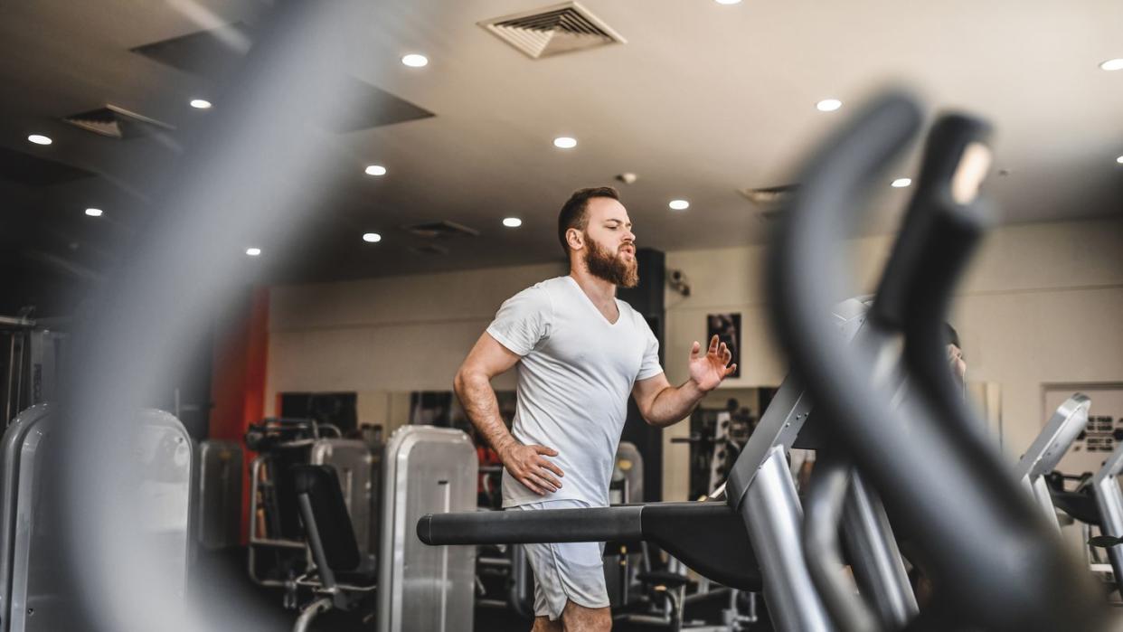 athletic male running on treadmill track in gym