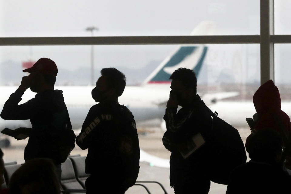 FILE - In this Feb. 4, 2020 file photo, people wearing masks line up for departure at Hong Kong airport in Hong Kong. An analysis of U.S. Commerce Department travel entry records and private aviation data obtained by The Associated Press shows that nearly 8,000 Chinese nationals and foreign residents of Hong Kong and Macao entered the U.S. on more than 600 commercial and private flights in the first three months after a ban was imposed on Feb. 2, 2020. (AP Photo/Achmad Ibrahim)