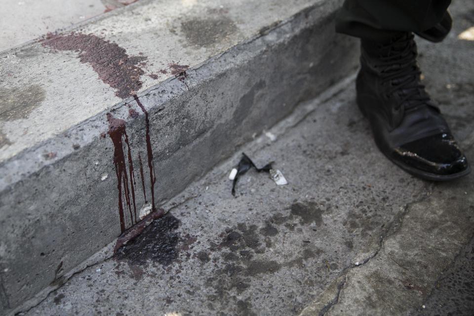 A blood splatter and debris rests on the pavement near the scene of an explosion targeted at an anti-government People's Democratic Reform Committee (PDRC) protest march in the Pathumwan district, Friday, Jan. 17, 2014, in Bangkok. Dozens of people were wounded in the capital Friday when an explosion hit anti-government demonstrators marching through Bangkok in broad daylight, an ominous development that raises tensions in the country’s political crisis and the specter of more bloodshed to come. (AP Photo/John Minchillo)